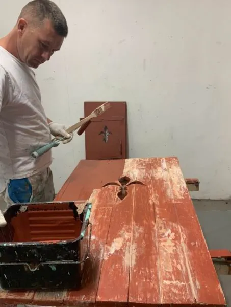 Volet peint en rouge sur l’établi, la peinture partant par écailles