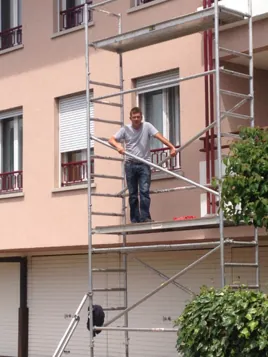Échafaudage roulant contre un immeuble, un peintre au travail
