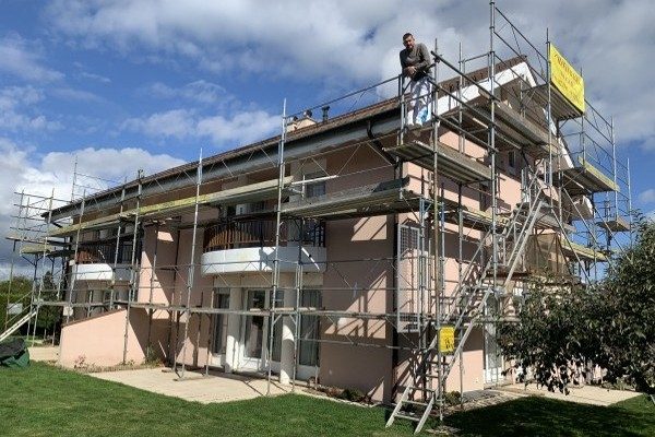 Échafaudage dressé contre une maison à balcons, avant la peinture de la façade