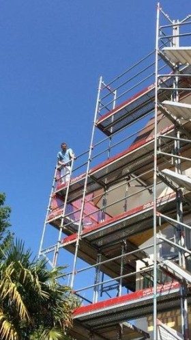 Peintre tout en haut d’un échafaudage, façade sur plusieurs niveaux