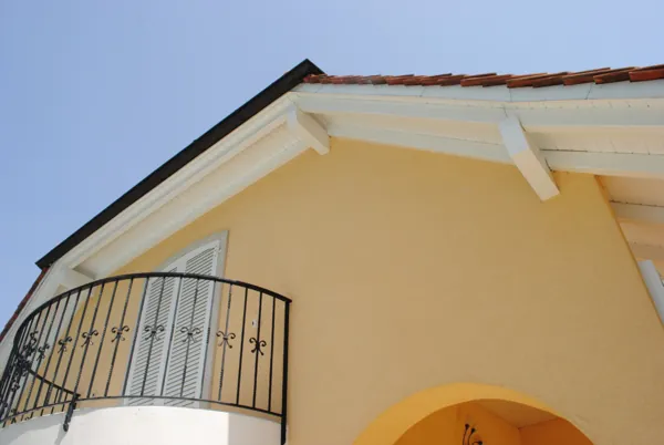Rive de toit et balcon bois traités, maison aux murs clairs