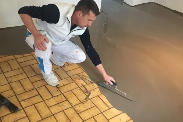 Enduit passé à la lisseuse sur un vieux carrelage jaune