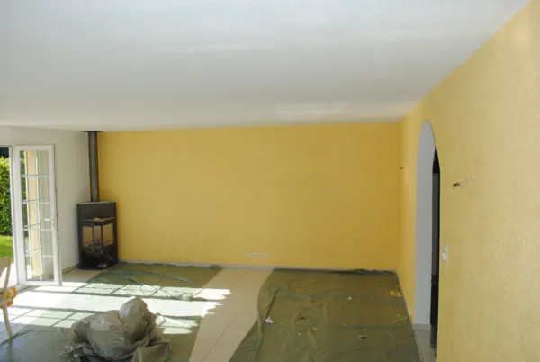 Mur jaune vif derrière un poêle, sol encore protégé