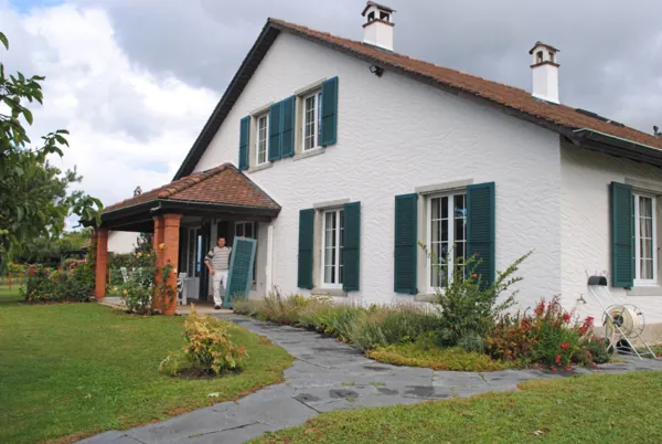 Volets bois vert foncé remis en peinture sur une maison aux murs blancs